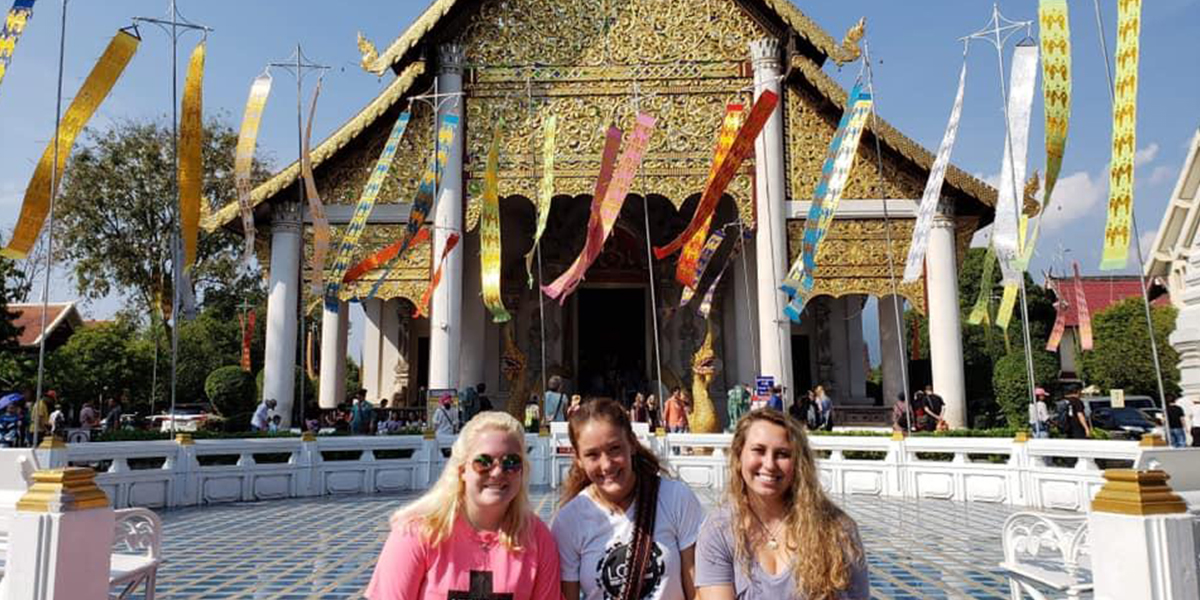 Students posing in front of a temple in Tailand