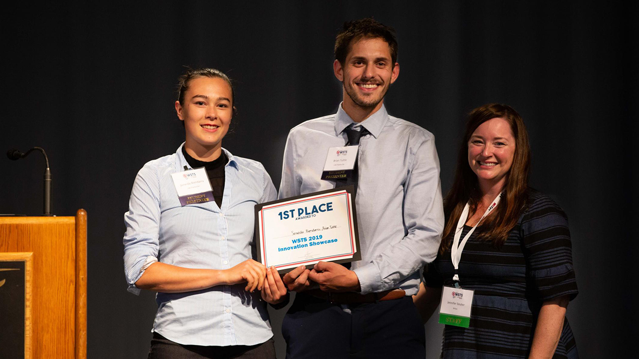 Seneida Biendarra and Brian Tuttle receive first place in the WiSys Innovation Showcase for their rock-climbing innovation, "Skillzboard."