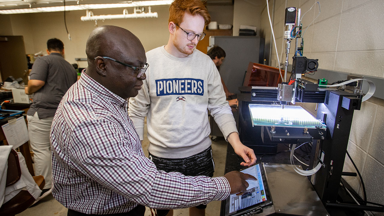 Dr. John Obielodan works with a student on set up for test fabrications.