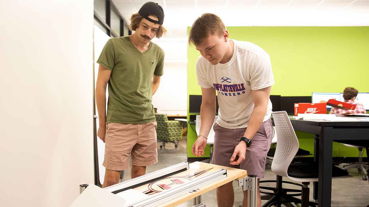 Jack Hutchinson and Ryan Nottestad work on their prototype of an automated diaper tab stacker.