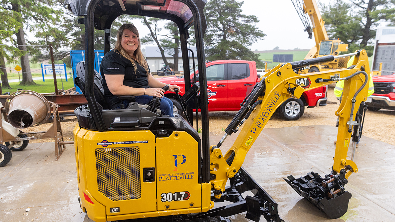 Gretchen Bockenhauer, Construction Management program coordinator and assistant professor, celebrates the mini-excavator, donated by Miron Construction.