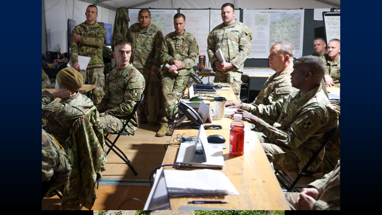 Lucas Anderson (seated left) in Germany with Brig. Gen. Louis Mitchell during a deployment, Oct. 14–Nov. 3, 2025. Photo credit: Photo courtesy of the U.S. Department of Defense and Staff Sgt. Anthony Torres via DVIDS. The appearance of U.S. Department of Defense (DoD) visual information does not imply or constitute DoD endorsement.