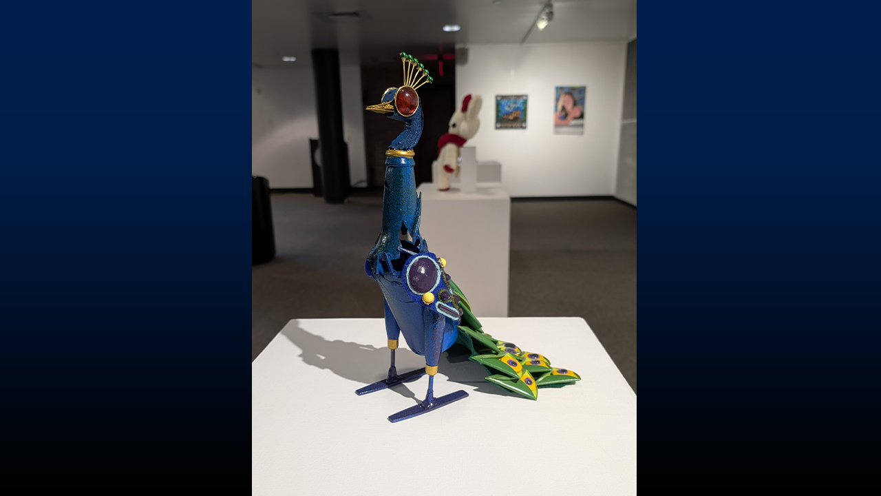 A peacock made of found objects called Recycled Peacock by Elizabeth Ringberg of Platteville High School stands confidently on a pedestal in Nohr Gallery.