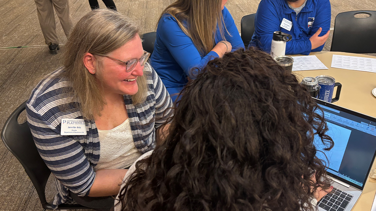 Woman helping another look over the schedule on the computer. 