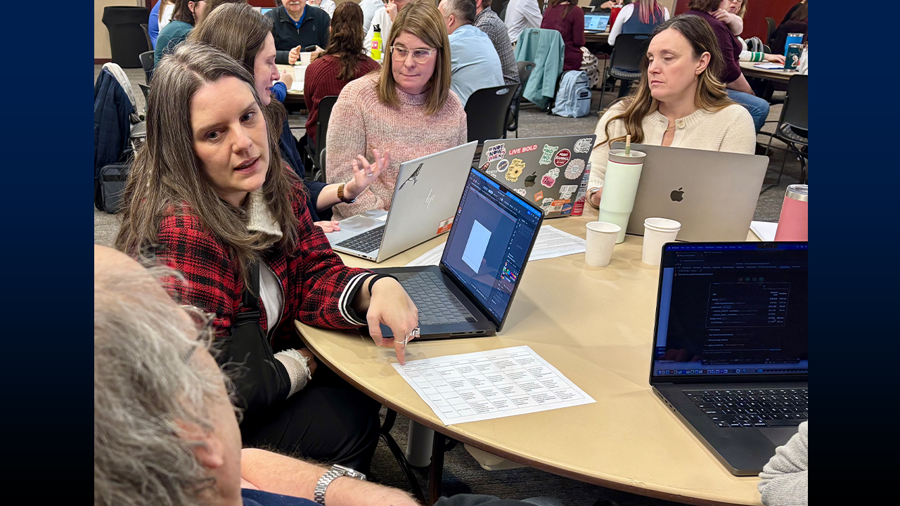 Woman speaking with a co-worker at a table. 