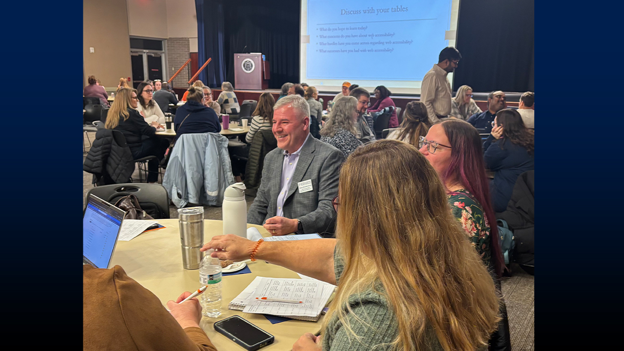 Man sitting at table speaking with group. 