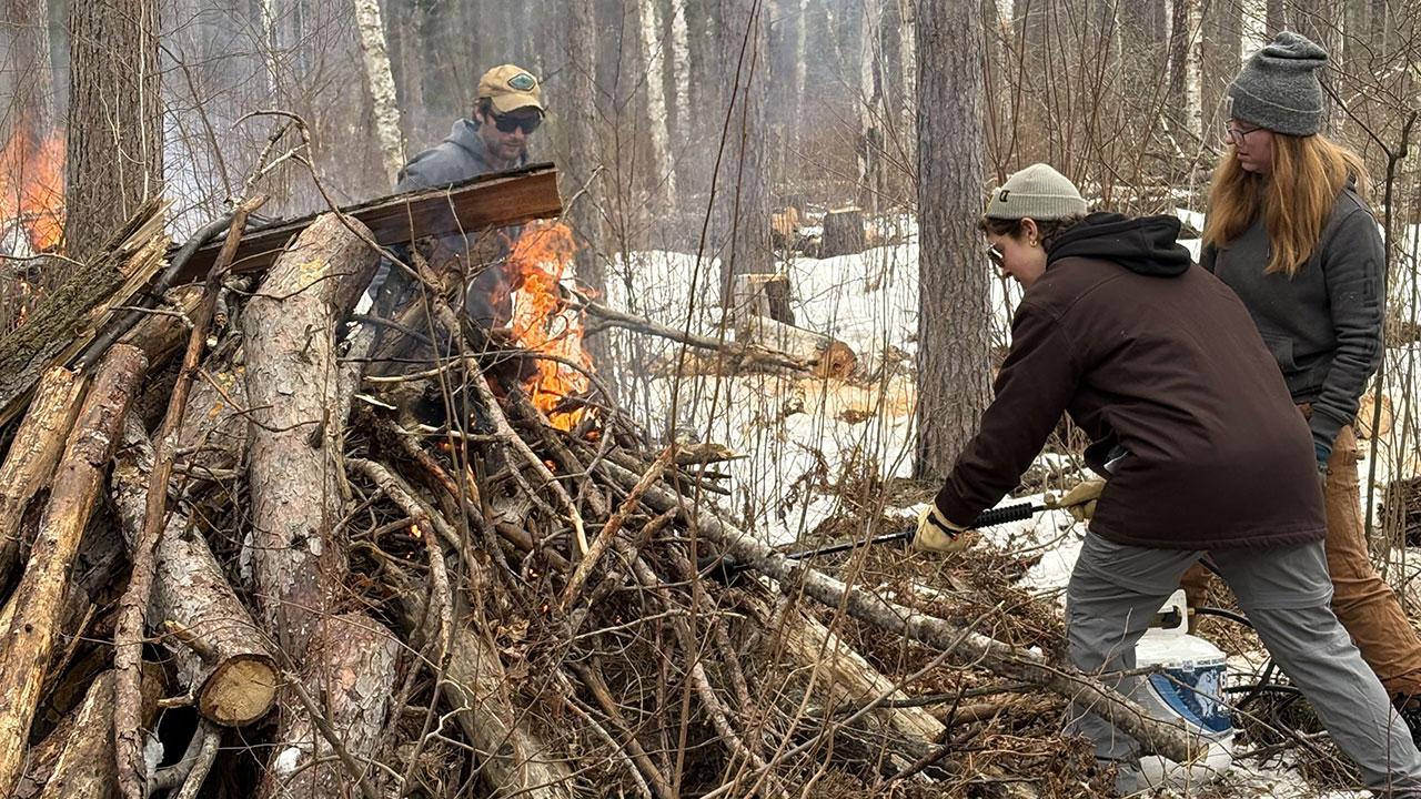 Three individuals tending to a fire