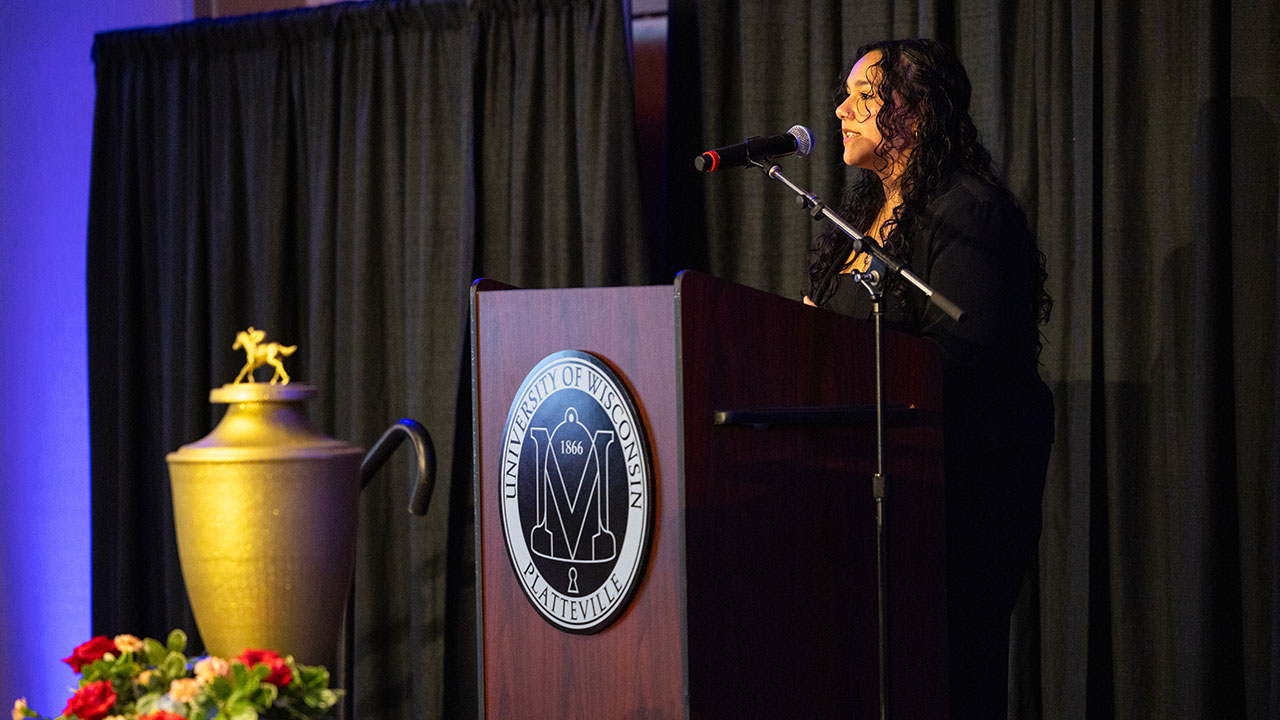 A female speaker standing at a podium in front of a black backdrop