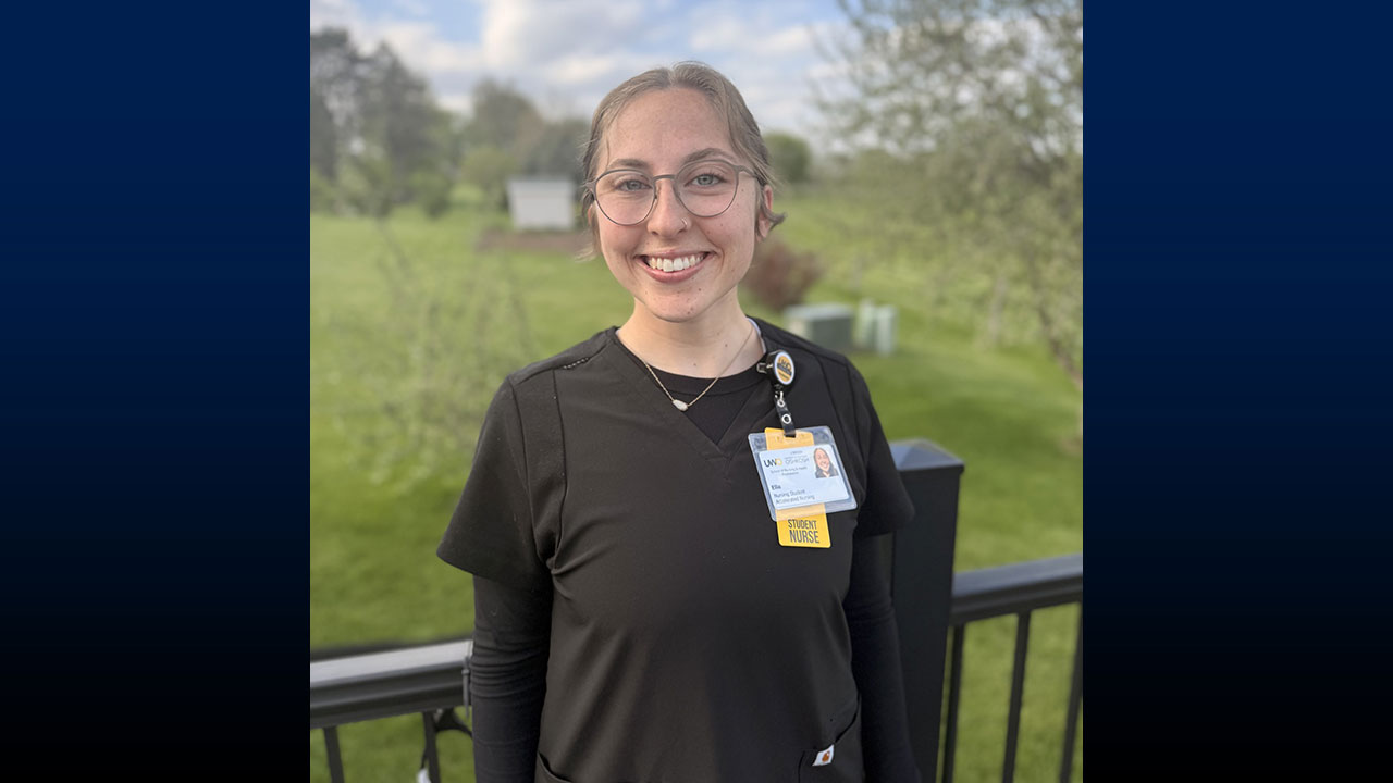 Blond woman in black scrubs smiling while standing outdoors.