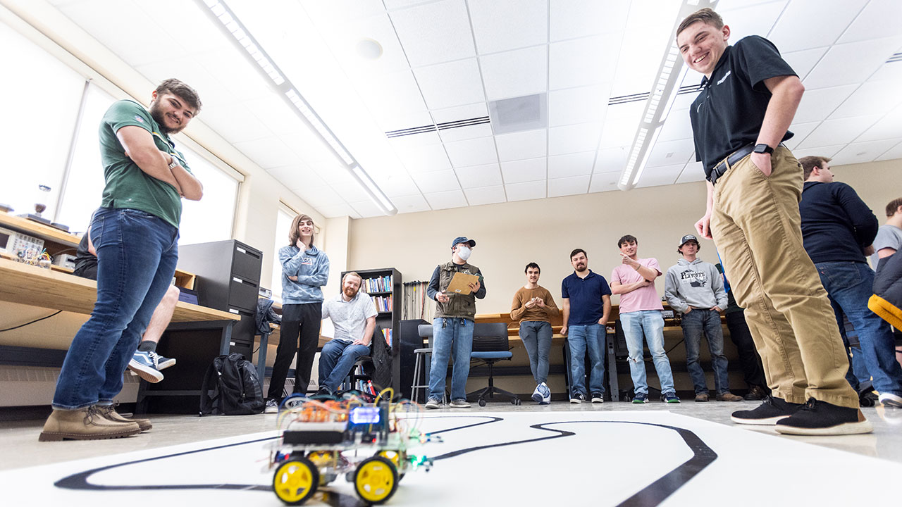 Group of students standing in a semi circle around a remote control vehicle