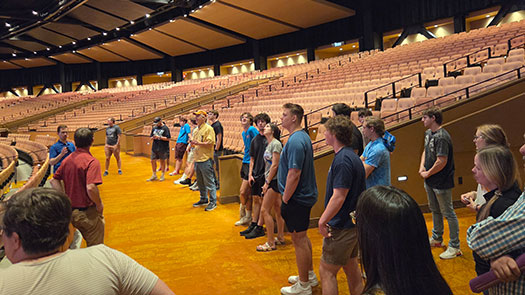 Group of students and faculty standing in an auditorium