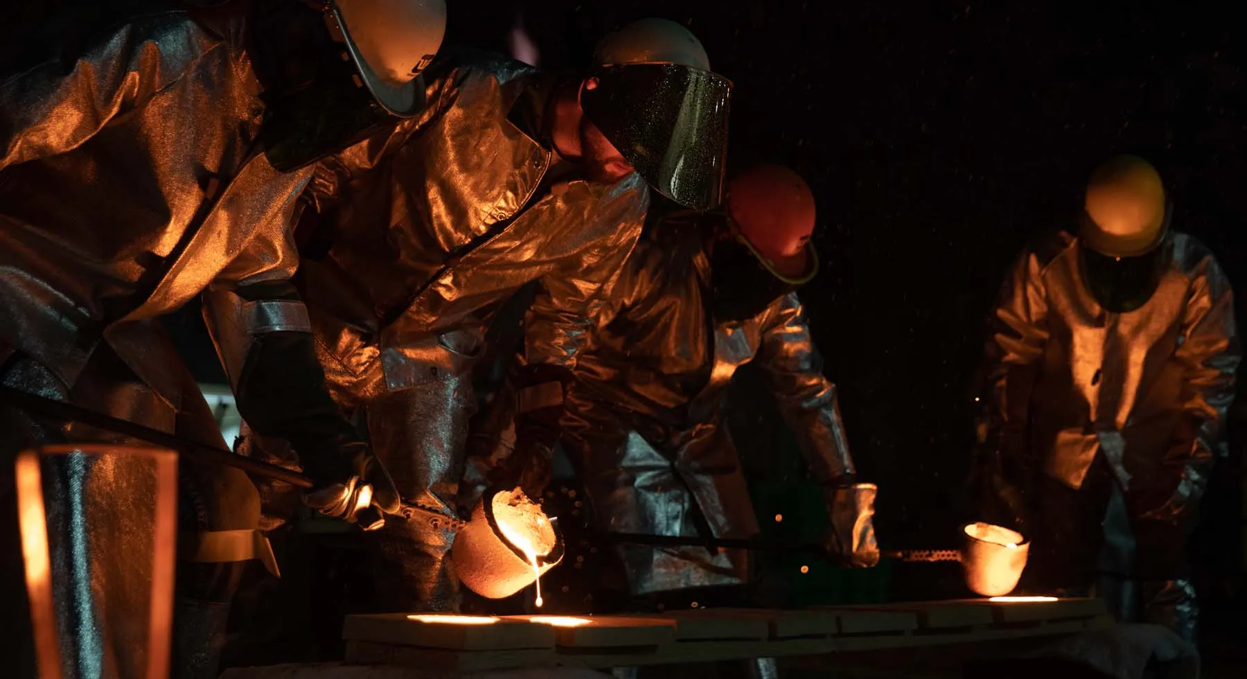 Workers in protective suits pour liquid metal into castings at UW-Platteville's foundry.