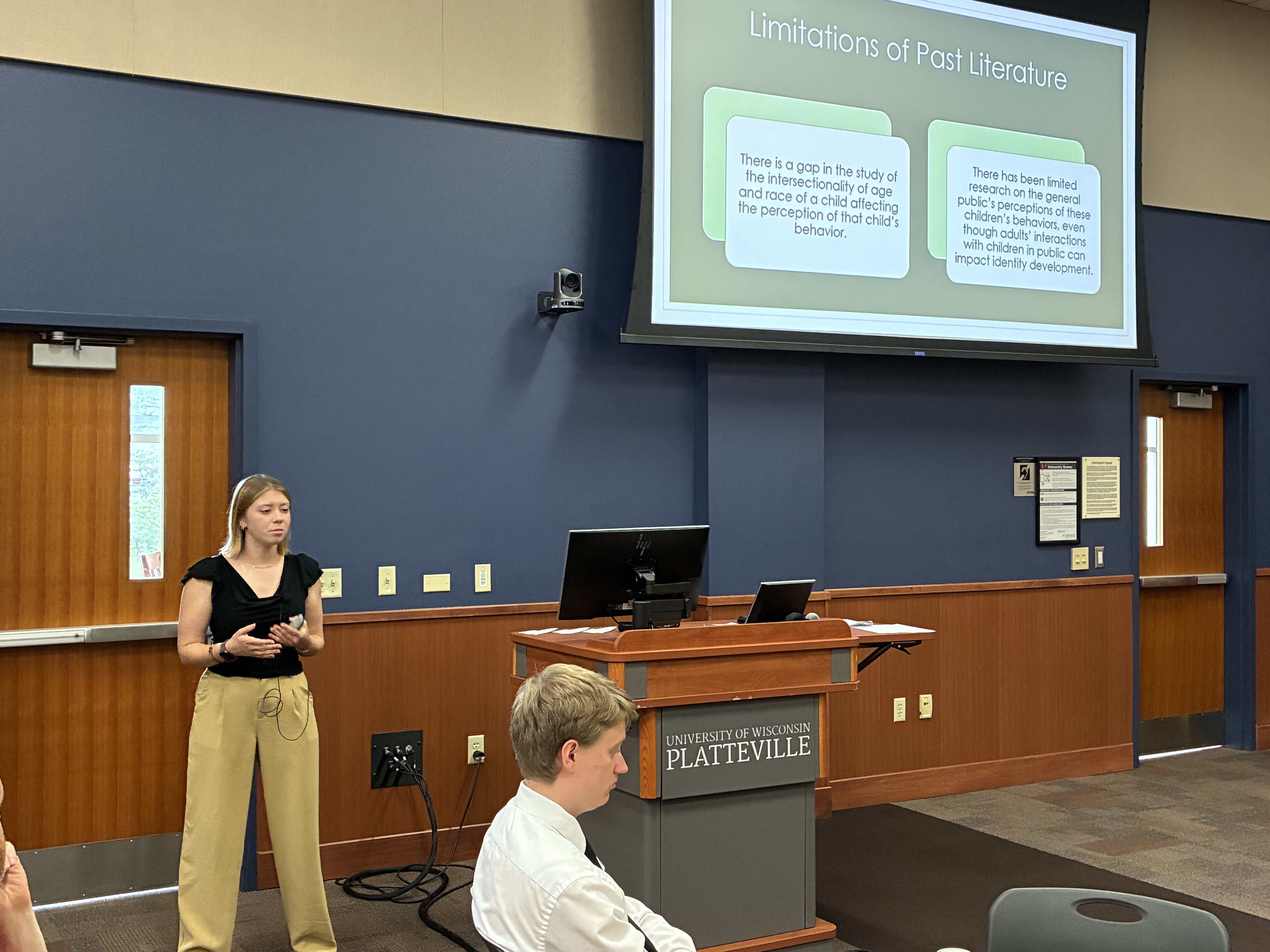 UW-Platteville sophomore Kyli McCorkle stands in front of a podium and screen in a meeting room during her Summer Scholars presentation Monday, July 20, 2026.