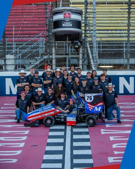 Members of the UW-Platteville racing team poses as a group with their car on the track at the 2026 Formula SAE Michigan competition in May.
