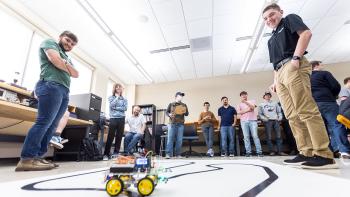 Group of students standing in a semi circle around a remote control vehicle