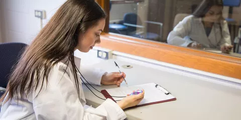 Kornely monitors participants through a one-way window as they complete the Trier Social Stress Test.