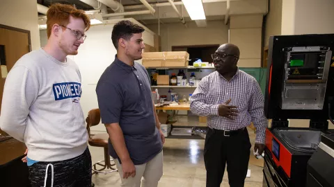 Dr. John Obielodan explains the workings of a newly acquired selective laser sintering machine to some of his students in the lab.