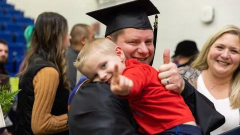 Graduate Troy Dirks (Master of Science in Organizational Change Leadership ’22) celebrates with his family after his fall 2022 commencement ceremony.