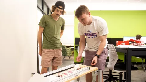 Jack Hutchinson and Ryan Nottestad work on their prototype of an automated diaper tab stacker.