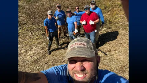 Schute, pictured in front with the grounds crew, working diligently to clean the retention ponds, ensuring a clean and well-maintained environment.