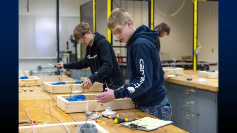 Two students working at a table on a project