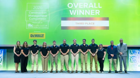 Large group of UW-Platteville students and faculty in front of green background while accepting an award