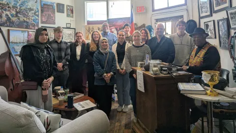 A large group of people standing next to a grand piano in a Zazz museum