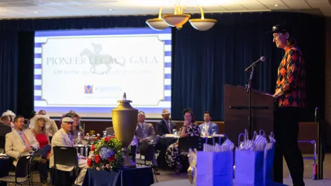 Woman standing at a podium, presenting to a room of seated guests
