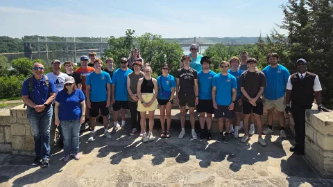 Group of students and faculty posing in front of a bridge