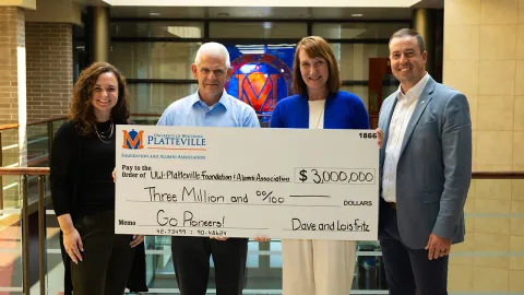 UW-Platteville Foundation and Alumni Association Executive Director Bridget Wallace, TRICOR Insurance CEO Dave Fritz, Chancellor Tammy Evetovich and Foundation and Alumni Association Major Gifts Director James Collins pose with a giant carboard check in Ullsvik Hall. 