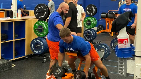 UW-Platteville football strength coach Paul Goodman helps a player with chest-supported rows during a workout at the Pioneer Activity Center.