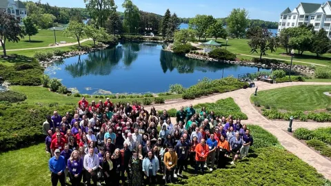 Universities of Wisconsin faculty gather around a pond at the 2026 Faculty College retreat at Osthoff Resort in Elkhart Lake, Wisconsin.