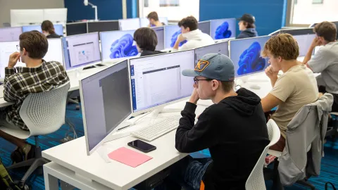 Students attending a coding class at computers in a classroom setting.