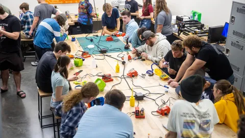 Students work with toys on a long wooden table at UW-Platteville's 2025 Holiday Toy Hack.
