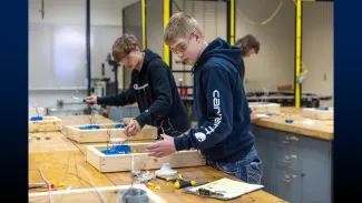 Two students working at a table on a project
