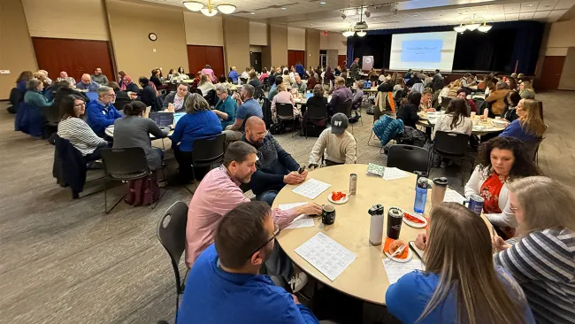 People around tables listening to presentation.