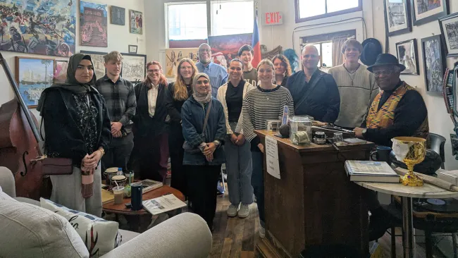 A large group of people standing next to a grand piano in a Zazz museum