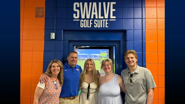 Group of individuals standing in front of an orange and blue wall, beneath the words "Swalve Golf Suite."