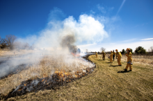 Photo of team in front of field fire on campus.