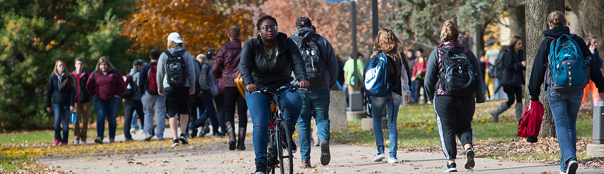 Students walking and biking on campus in fall