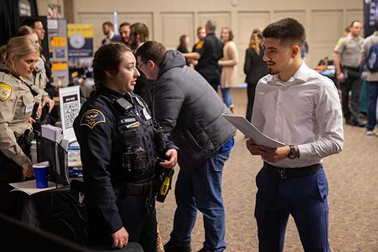 UW-Platteville student talks with a police officer at a career fair
