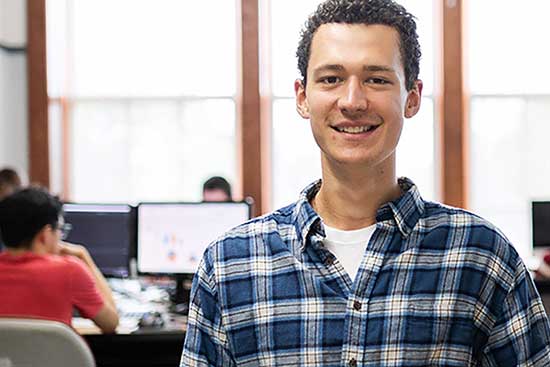 UW-Platteville student stands in computer lab looking at camera