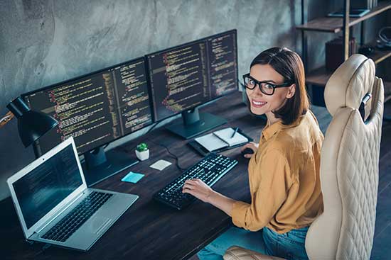 Professional woman coding on a multiple display computer setup