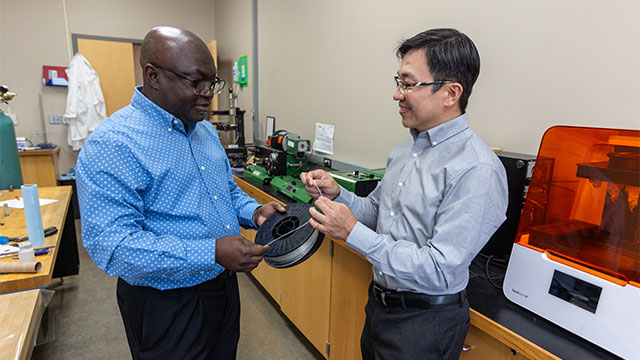 Dr. John Obielodan and Dr. Joseph Wu stand in lab assessing filament