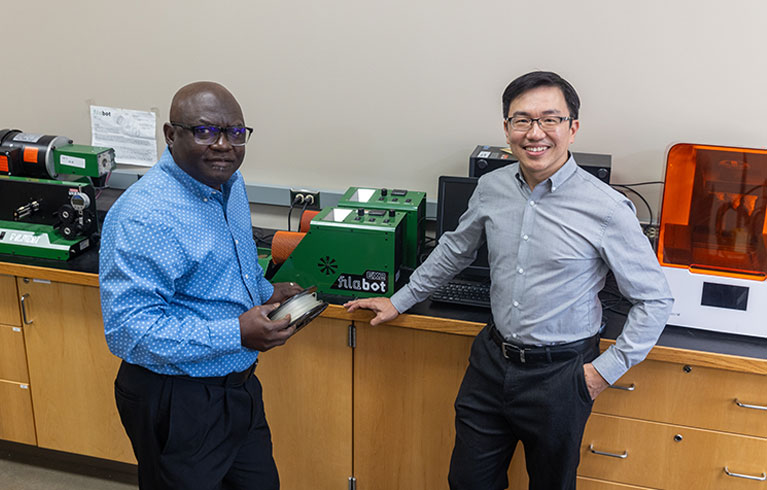 Dr. John Obielodan and Dr. Joseph Wu stand in lab
