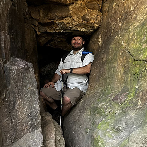 Berglund stands in cave entrance.