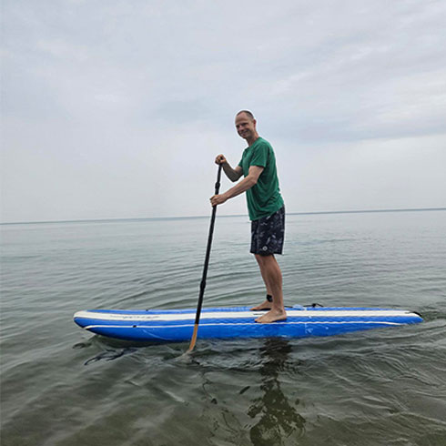 Frayer standing on a paddleboard in a lake.