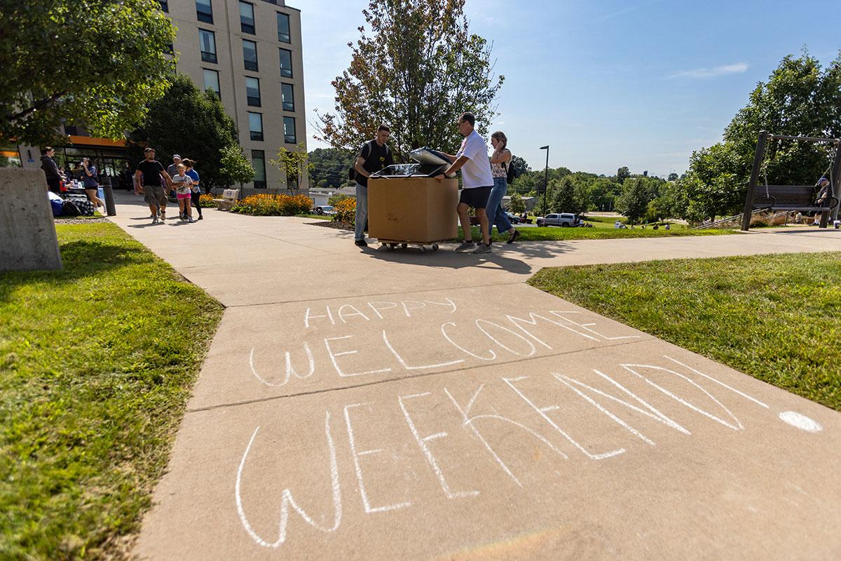 Two UW-Platteville students in orange shirts holding welcome signs on move in day