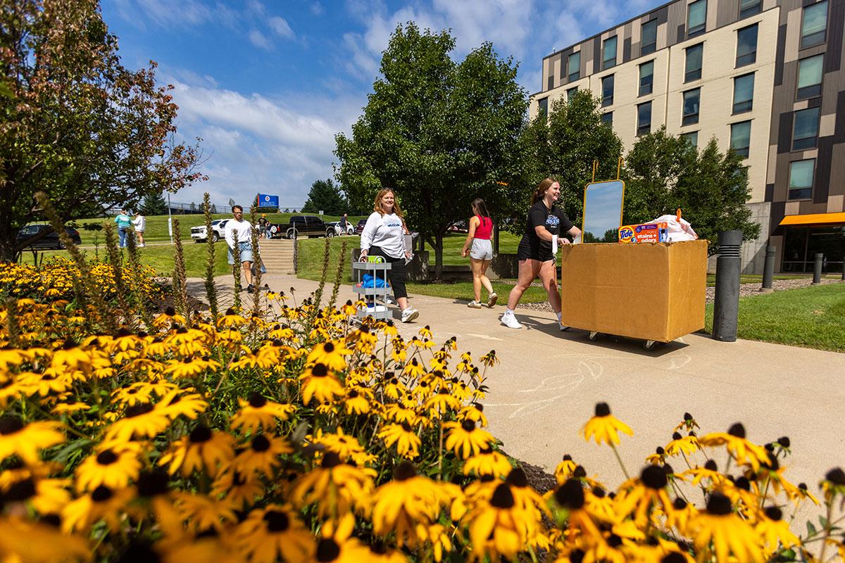 Two UW-Platteville students in orange shirts holding welcome signs on move in day