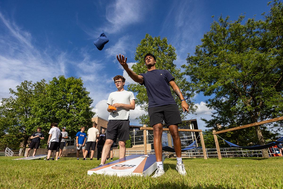 Two UW-Platteville students in orange shirts holding welcome signs on move in day